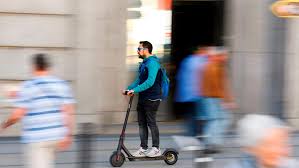 Hombre desplazándose por la ciudad en un patinete eléctrico